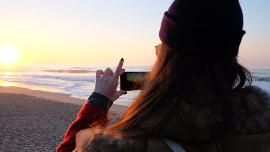 girl taking a picture of a sunset