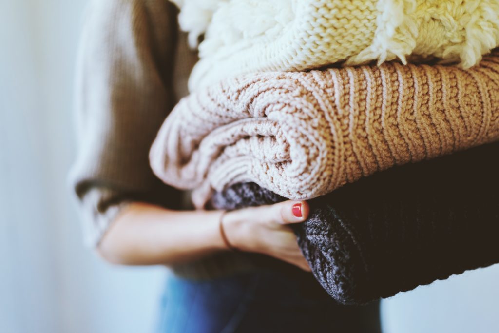 girl holding pile of clothes